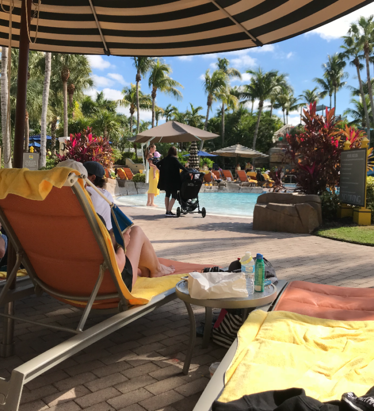 a group of people sitting in a lounge chair by a pool
