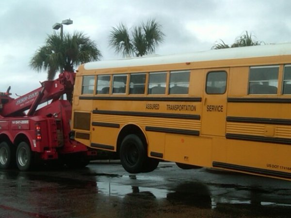 a yellow bus being towed by a tow truck