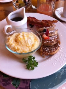 a plate of breakfast with a bowl of mashed potatoes and bacon