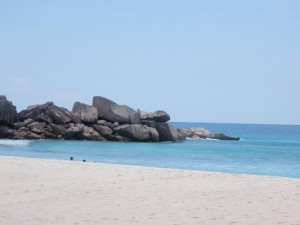 a sandy beach with rocks in the water