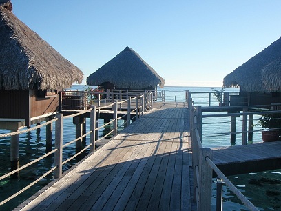 a wooden dock with straw huts on the water