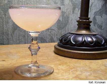 a glass of pink liquid next to a lamp