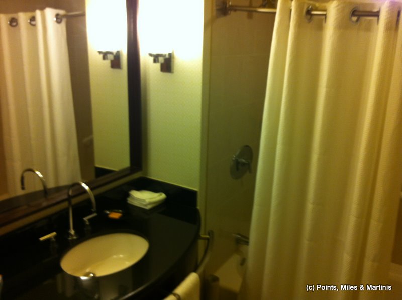 a bathroom with a black countertop sink and a white shower curtain