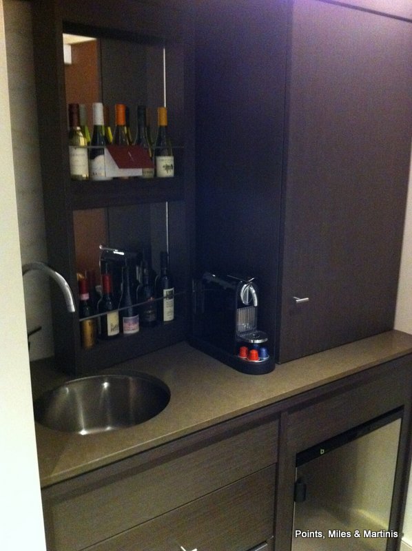 a kitchen counter with a sink and a cabinet with bottles of wine