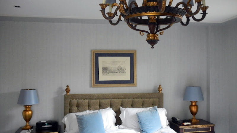 a bed with a chandelier and a picture on the wall