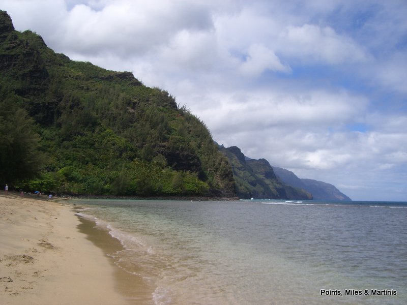 a sandy beach with a large body of water and a hill