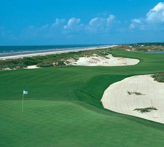 a golf course with sand dunes and a flag with Pebble Beach Golf Links in the background