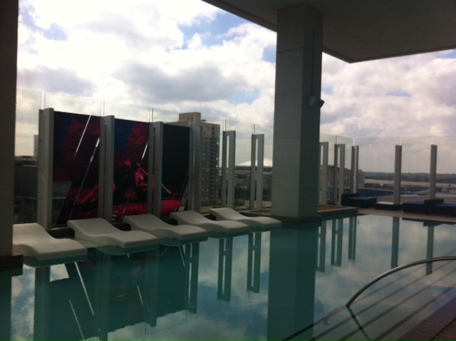 a pool with lounge chairs and a large glass wall