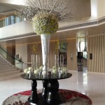 a large vase with flowers on a table in a lobby