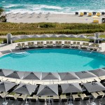 a swimming pool with umbrellas and chairs on the beach