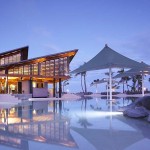 a pool with a building and a large umbrella