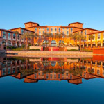 a building with palm trees and a pool of water