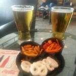 a plate of snacks and beer on a table