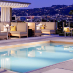 a pool with chairs and tables in front of a city