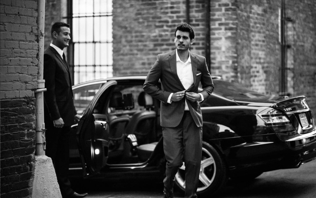 a man in a suit walking next to a car