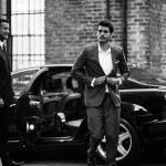 a man in a suit walking by a car