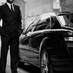 a man in a suit and tie standing next to a car