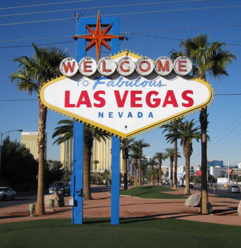 a sign with palm trees and buildings in the background with Welcome to Fabulous Las Vegas sign in the background