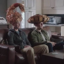 two men sitting on a couch wearing hats