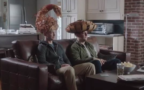 two men sitting on a couch wearing hats