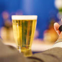 a person holding a cell phone and a glass of beer
