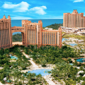 a group of buildings with palm trees and a pool with Atlantis Paradise Island in the background