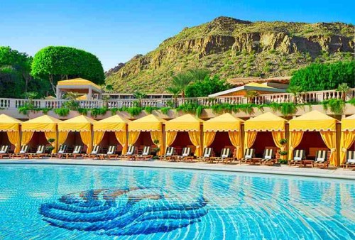 a pool with yellow awnings and a mountain in the background