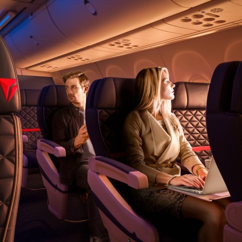 a man and woman sitting in an airplane with a laptop