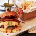 a burger with bacon and pickles on top