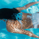 a woman swimming underwater in a pool