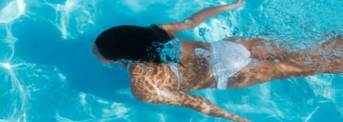 a woman swimming underwater in a pool