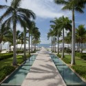 a long walkway with palm trees and a pool with Laie Hawaii Temple in the background