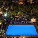 a pool with chairs and trees at night