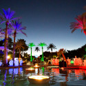 a pool with palm trees and a lit up fire pit