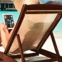 a woman sitting in a chair on a beach with a laptop