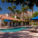 a pool with chairs and umbrellas in front of a house