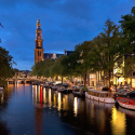 a river with boats and buildings and a tower in the background