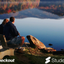 a couple sitting on a bench looking at a lake