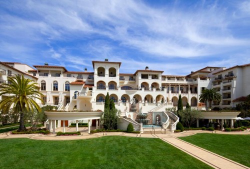 a large white building with a fountain and a lawn