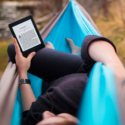 a person lying in a hammock reading a book