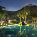 a pool with palm trees and buildings in the background