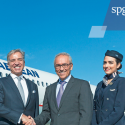 a group of people in suits and ties shaking hands in front of an airplane