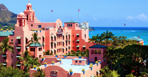 a pink building with a blue sky and water in the background with Don CeSar in the background