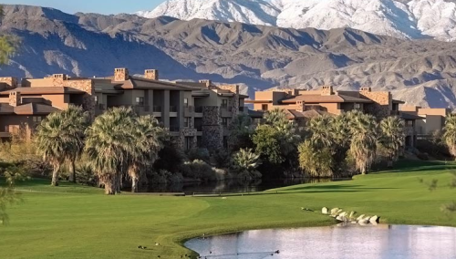 a golf course with a lake and mountains in the background