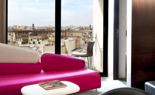 a pink couch in a room with a view of a city