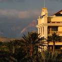 a building with palm trees and mountains in the background