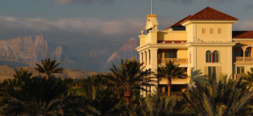 a building with palm trees and mountains in the background