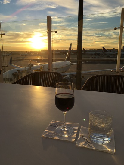 a glass of wine and a glass of water on a table with airplanes in the background
