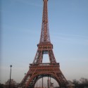 a large metal tower with a blue sky with Eiffel Tower in the background