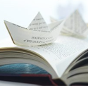 a paper boat on an open book